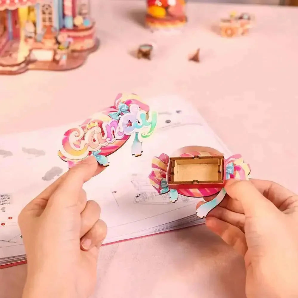 Hands assembling a pink Candy Workshop component over illustrated instructions.