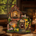 Dreamy Cottage miniature house with a rabbit in the upper window and flowers around the entrance.