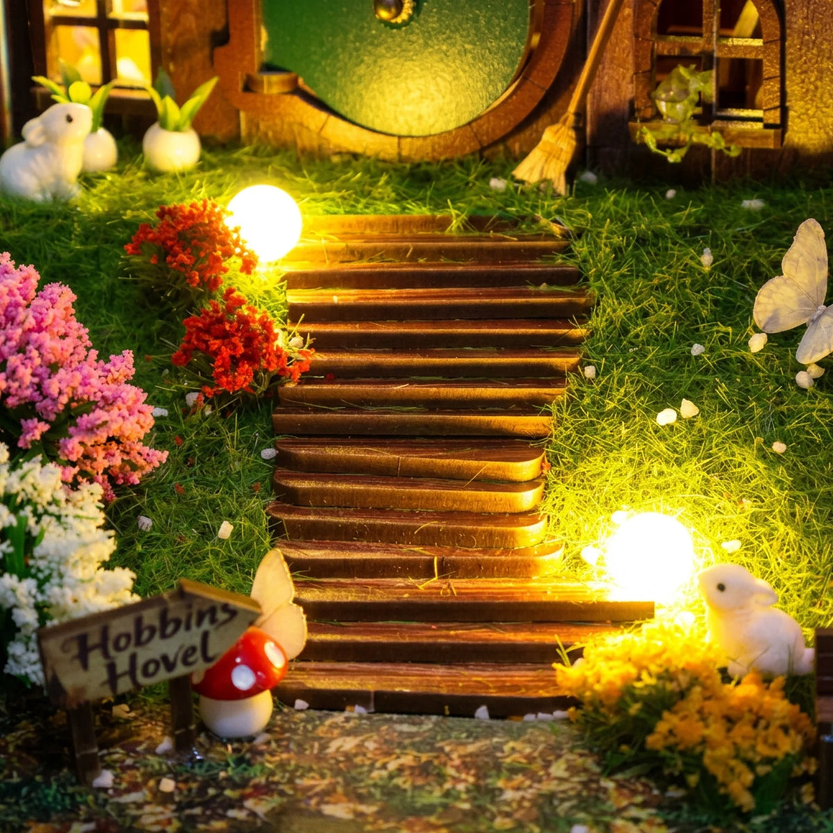 Hobbins Hovel garden steps with small lamps, flowers, rabbits and a miniature sign.