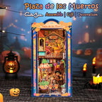 Plaza de los Muertos festive street book nook against a dark backdrop with small pumpkin decorations.
