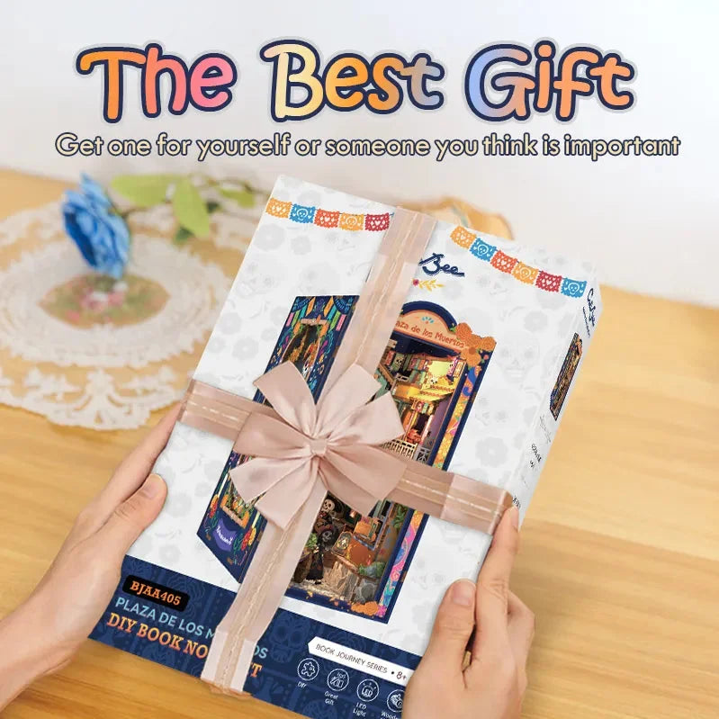 Hands holding a Plaza de los Muertos kit box tied with a ribbon.