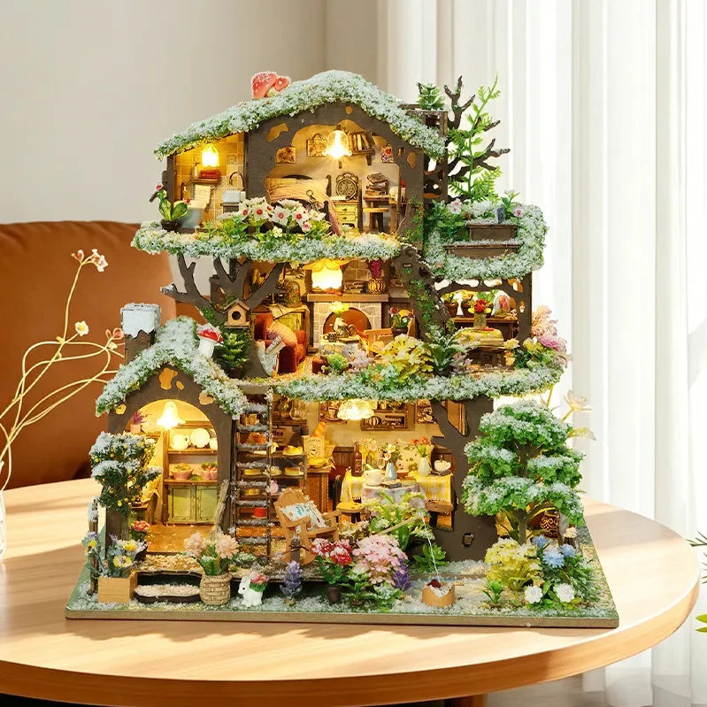 Time Treehouse snow-roof edition displayed beside a window, with white-tipped foliage and warm lights.